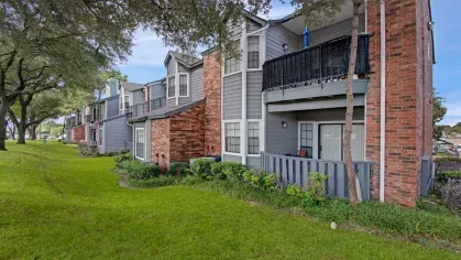 Exterior view of apartment buildings with brick and gray siding, balconies, and green lawn