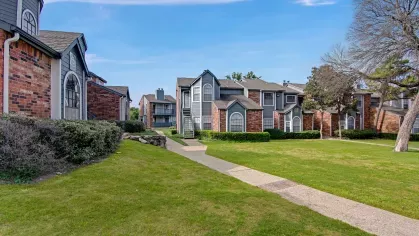 Scenic sidewalk pathway between apartment buildings with trimmed bushes and well-kept lawns