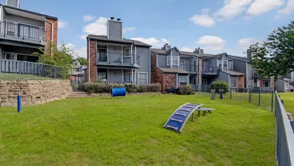 Dog park featuring tunnels, ramps, and play structures surrounded by residential buildings