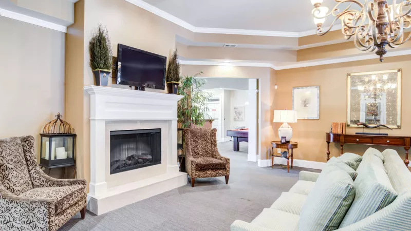 Elegant resident lounge featuring a fireplace, plush seating, and a TV mounted above the mantel.