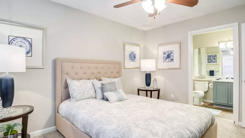 Spacious bedroom with a tufted headboard, neutral bedding, and attached bathroom.