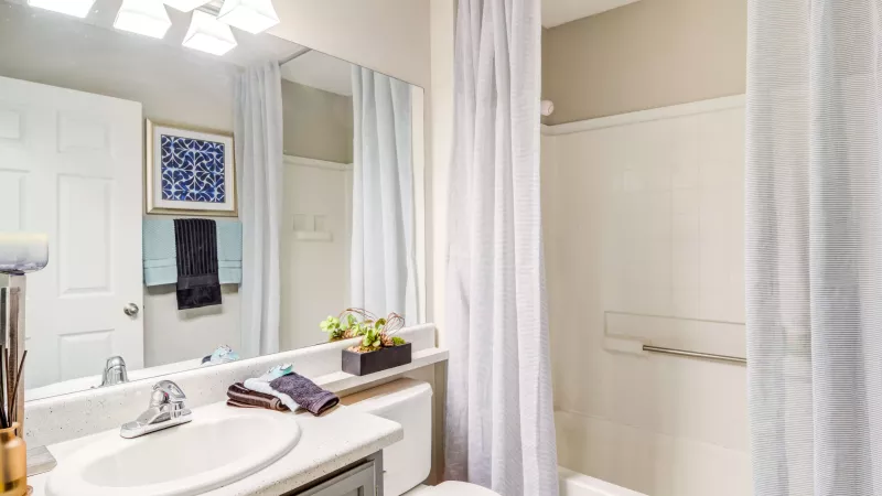 Clean bathroom with a shower-tub combo, framed mirror, and ample countertop space.
