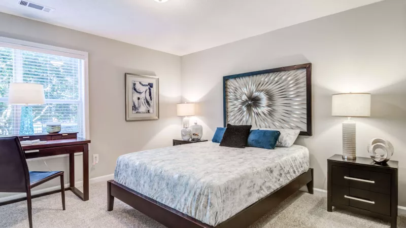 Bedroom with a decorative feature wall, work desk, and bright window.