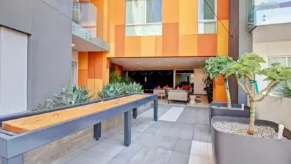 An outdoor shuffleboard court surrounded by greenery and modern apartment balconies, providing a fun recreational space.