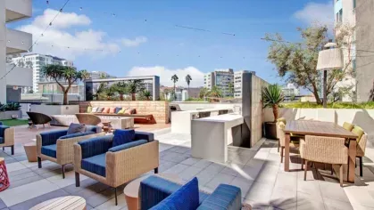 A beautifully designed open-air lounge with a mix of cushioned seating, fire pits, and cityscape views for relaxation.