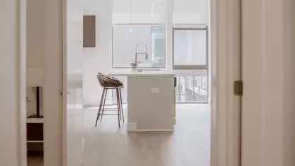Open-concept kitchen with a spacious island, stylish pendant lighting, and a built-in washer and dryer in the background.