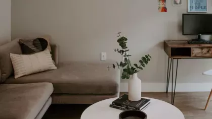 A close-up of a modern kitchen corner, showcasing a dark glossy backsplash, white cabinetry, and a built-in microwave.