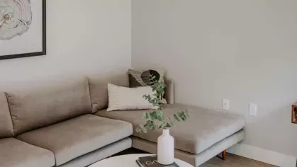 A beautifully styled living room with a gray sectional, geometric wall art, and a coffee table with decorative accents.