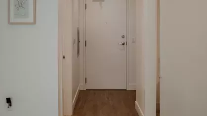A well-lit entryway with warm wood flooring, leading into the modern living space of an Industry Columbus apartment.
