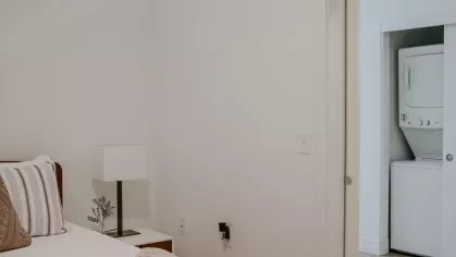 A well-lit bedroom with a direct view of the in-unit washer and dryer, offering convenience and comfort in modern apartment living.