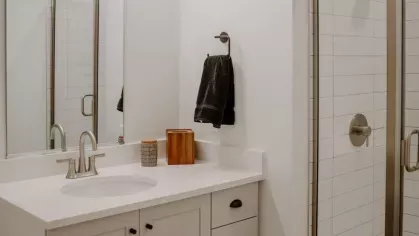 A contemporary bathroom featuring a sleek vanity with white cabinetry, a large mirror, and a glass-enclosed shower with white subway tile.