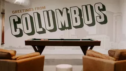 Resident lounge featuring a pool table and a large "Greetings from Columbus" mural for a welcoming atmosphere.