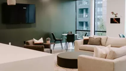 A sophisticated resident lounge with plush seating, a mounted TV, and a green accent wall, offering a comfortable gathering space.