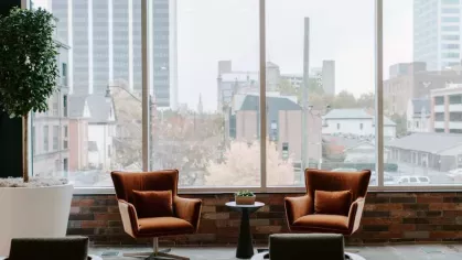 A stylish seating area with plush armchairs and a panoramic window overlooking the city skyline, creating a relaxing ambiance.