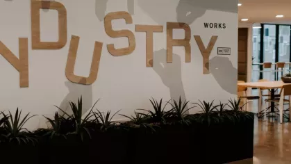 A modern coworking area with "Industry Works" signage, sleek black planters, and collaborative seating, designed for productivity.