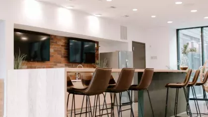 A modern community kitchen with a sleek white island, stylish pendant lighting, and high-end appliances at Industry Columbus Apartments.