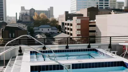 An open-concept lounge and kitchen area at Industry Columbus Apartments featuring a spacious seating arrangement, stylish artwork, and a "Greetings from Columbus" mural.