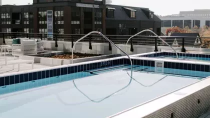 A bright and inviting seating area with large windows, plush chairs, and greenery at Industry Columbus Apartments, offering a perfect spot to relax or socialize.