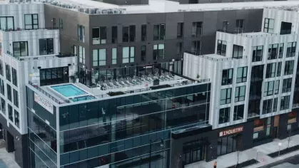 A communal dining space at Industry Columbus Apartments with long wooden tables, stylish chairs, and built-in booth seating, fostering a sense of community.