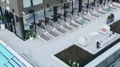 A rooftop pool area at Industry Columbus Apartments featuring a row of modern lounge chairs, cozy outdoor seating, and lush greenery, creating a stylish and relaxing retreat for residents.