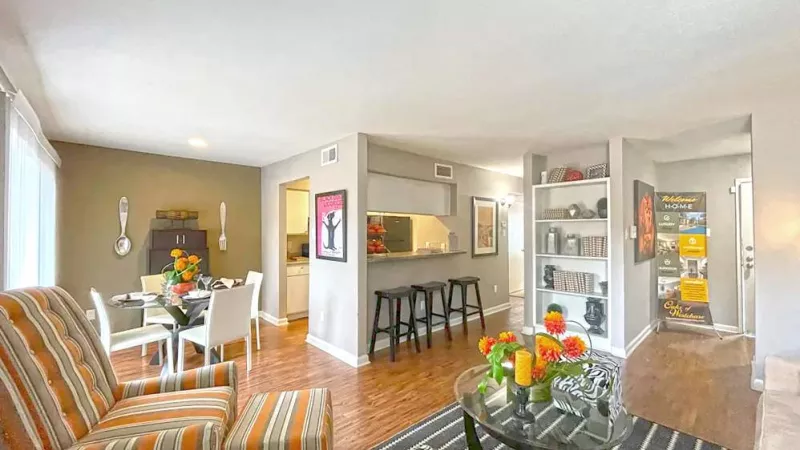 An open-concept living and dining area with hardwood-style flooring, built-in shelving, and chic furnishings.