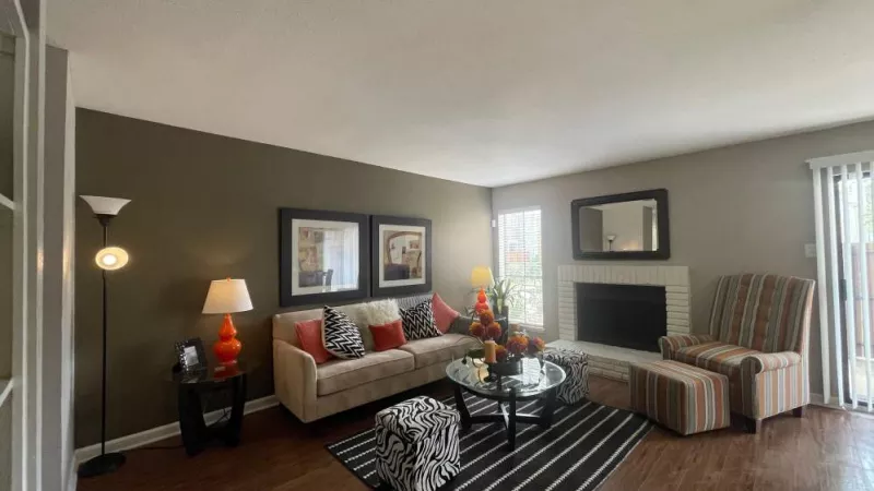 A beautifully designed living room with a fireplace, striped armchair, and neutral-toned walls for a contemporary feel.