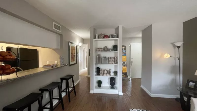 A bright and airy open-concept space featuring a bar counter with stools, built-in shelving, and a view of the entryway.