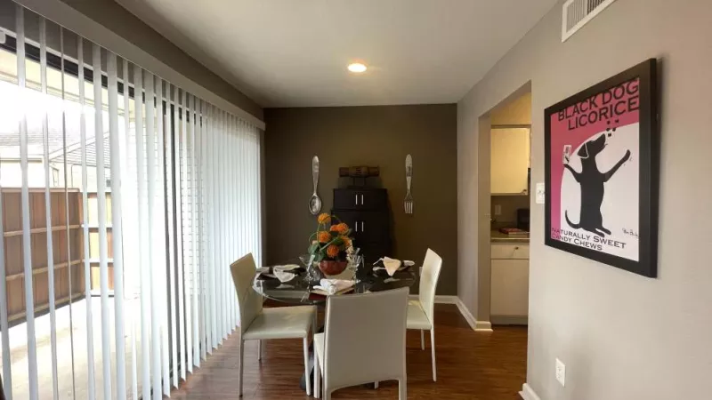 A contemporary dining space with bold decor, wall art, and a pass-through window to the kitchen, creating a seamless flow.