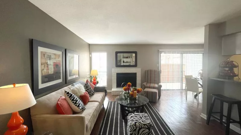 A spacious living room at The Oaks of Westchase Apartments featuring a cozy fireplace, plush seating, and contemporary decor with natural light from large windows.