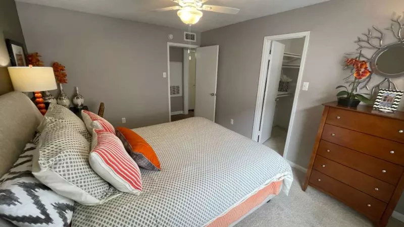 A well-furnished bedroom with a soft color palette, direct access to a walk-in closet, and modern decor for a relaxing ambiance.