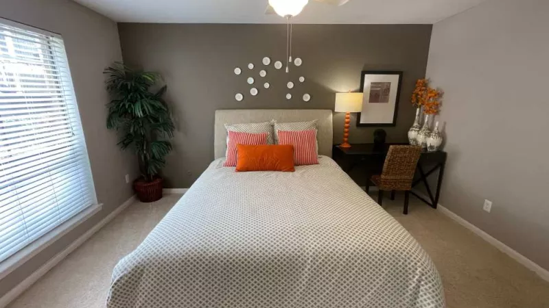 A bright and airy bedroom featuring a plush bed, stylish decor, and a workspace, enhanced by a large window that brings in ample natural light.