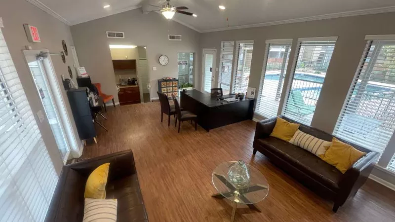 A high-angle view of the spacious clubhouse, showcasing large windows, elegant seating, and a well-lit office area.