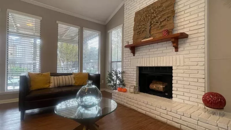 A cozy clubhouse corner with a white brick fireplace, contemporary furnishings, and warm décor for a relaxing atmosphere.