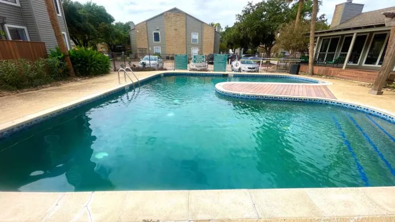 A close-up view of the community swimming pool with clear water, poolside seating, and a gated entrance for resident relaxation.