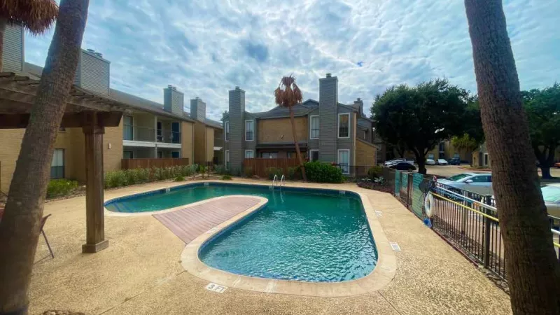 A relaxing poolside ambiance with palm trees and a well-maintained deck at The Oaks of Westchase Apartments, offering a serene environment for residents.