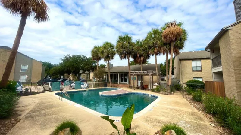 A spacious and inviting community pool at The Oaks of Westchase Apartments, with a beautifully landscaped area and plenty of seating options.