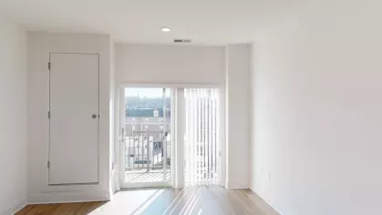 A bright and inviting empty room with large windows, natural light streaming in, and sleek wood flooring, perfect for a customizable living space.