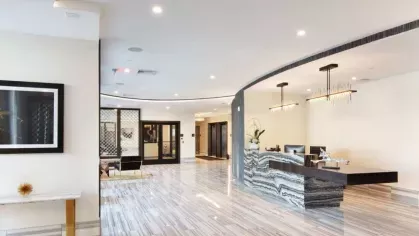 A sleek and stylish lobby with marble flooring, a curved reception desk, and elegant lighting.
