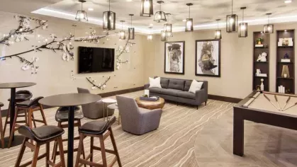 A chic lounge area with plush seating, a large wall-mounted TV, and elegant pendant lighting, perfect for social gatherings.