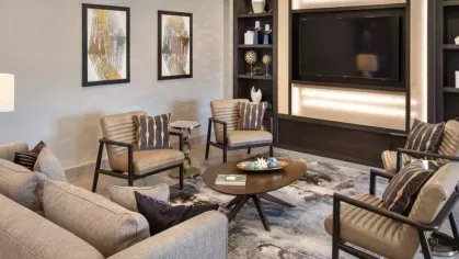 A sophisticated resident lounge with plush seating, decorative shelving, and a built-in entertainment system.