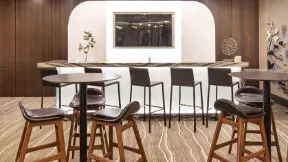 A chic social bar area with high-top seating, a backlit mirror, and dark wood paneling.