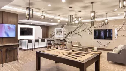 A vibrant game room with a sleek shuffleboard table, artistic wall decor, and contemporary lighting.