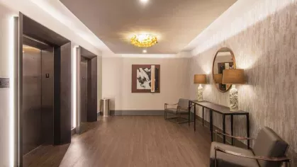 A luxurious elevator lobby with warm-toned wood flooring, stylish seating, and decorative accents.