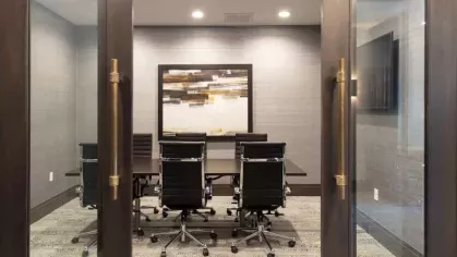 A stylish conference room with sleek black chairs, a modern table, and elegant glass doors for privacy.