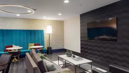 A cozy resident lounge with plush seating, a vibrant blue accent wall, and a sleek television display.