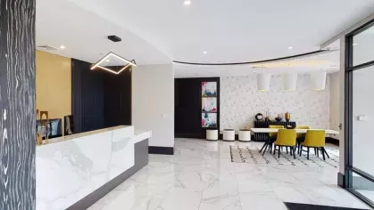 A sleek leasing office entrance featuring a curved marble reception desk and stylish lighting.
