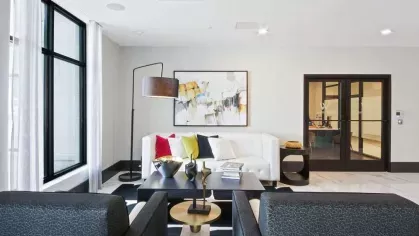 A professional conference room with sleek black chairs, a modern meeting table, and glass-paneled barn doors.