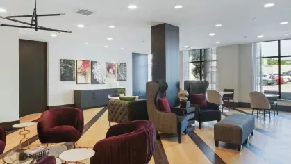 A vibrant resident lounge with a mix of contemporary and classic seating, bold decor, and ample natural light.