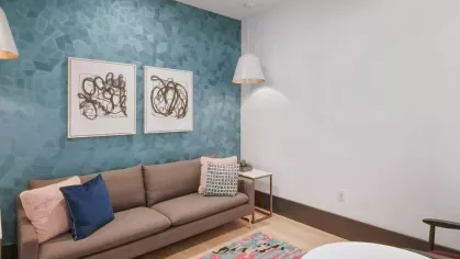 A cozy yet stylish resident lounge with deep blue seating, a flat-screen TV, and contemporary decor.