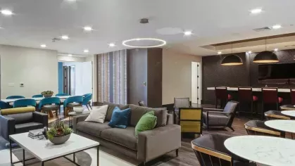 A spacious communal area with a mix of plush and accent seating, wooden flooring, and contemporary lighting.